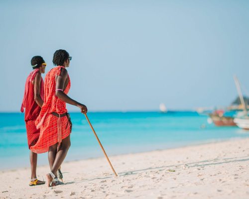 ZANZIBAR, TANZANIA - February 2016: Two Masai dressed in traditional clothes walking along the beach on Zanzibar, Tanzania